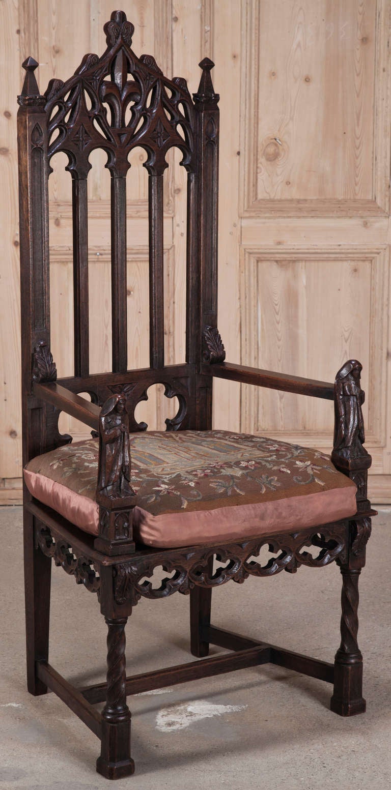 This impressive Gothic fauteuil was sculpted from solid old-growth French white oak during the mid-19th century revival coinciding with the transition to the last monarch of France. The timeless moorish arches are adorned with fleurs de lys paying