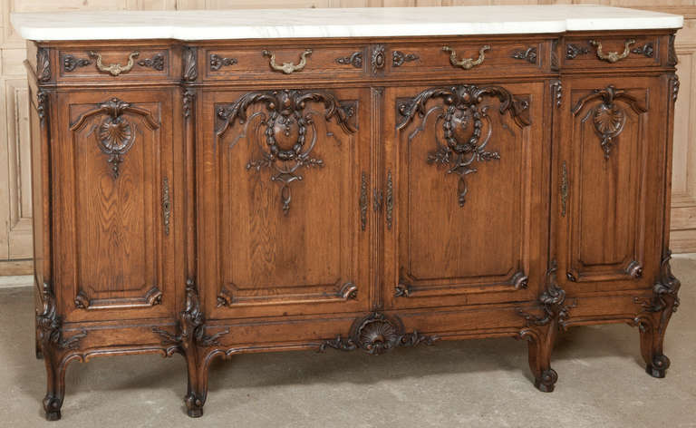 No one can deny the Regence style is one of France's greatest contributions to the world of design, and this stunning Vintage Marble Top Buffet, sculpted from dense, old-growth French white oak, is a splendid example of the genre!  The step-front