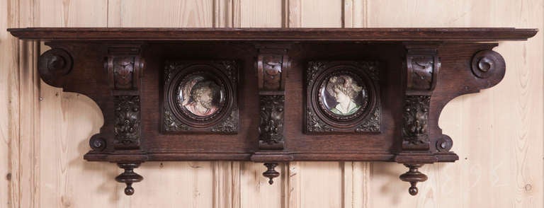 Hand-carved to perfection from old-growth European red oak, this elegant wall shelf was designed as a wedding gift, with portraits of the betrothed hand-painted on inset plaques, framed with foliates that complement the remainder of the carvings on