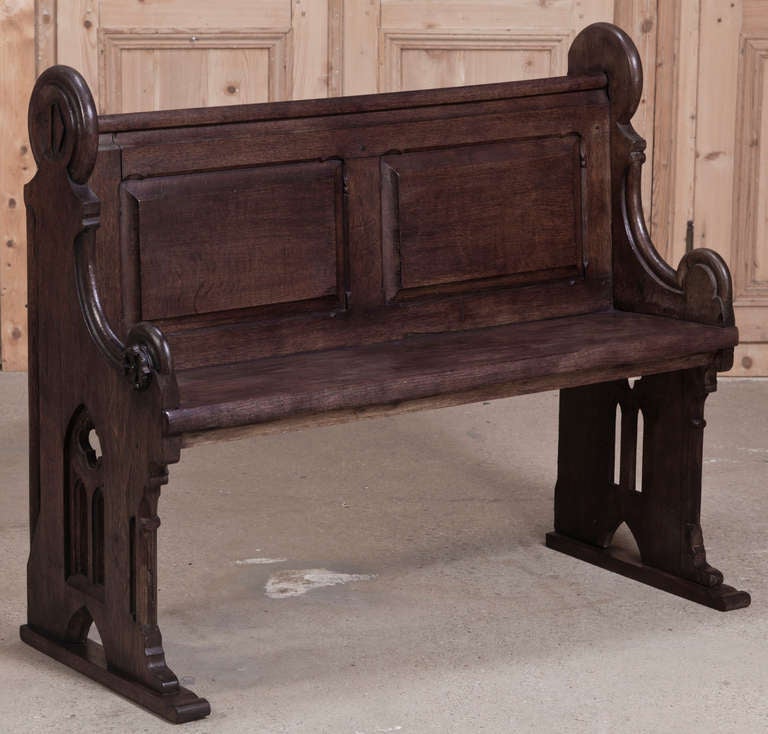 Hand-crafted from solid French white oak in the Gothic style, this well-preserved church pew was built to last for centuries! Classic architecture combines with plaquards atop the side supports with the row designation. The armrests end in