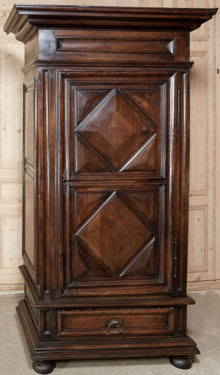 Entirely hand-made from old-growth French walnut, this bonnetiere exhibits the pyramidal form and bold molded detail prevalent during the latter half of the 17th century in rural France. 
Circa 1680s. 
Measures 89H x 51W x 30D.