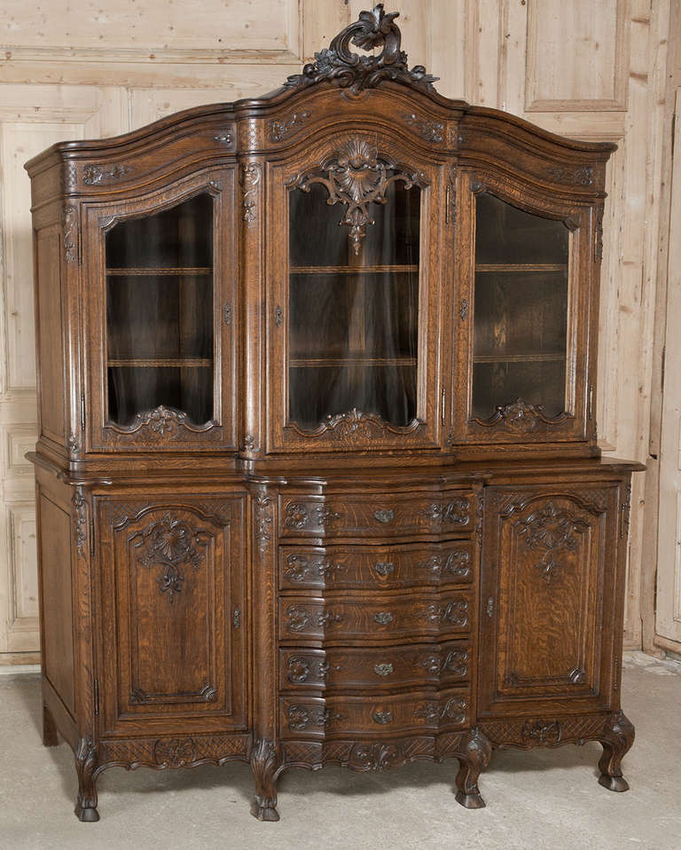 This vintage Country French Buffet was hand-crafted from solid oak in the Regence manner to provide enjoyment for generations!  Exquisite shell, floral and foliate carvings abound across the facade, and the majestically arched crown above the upper