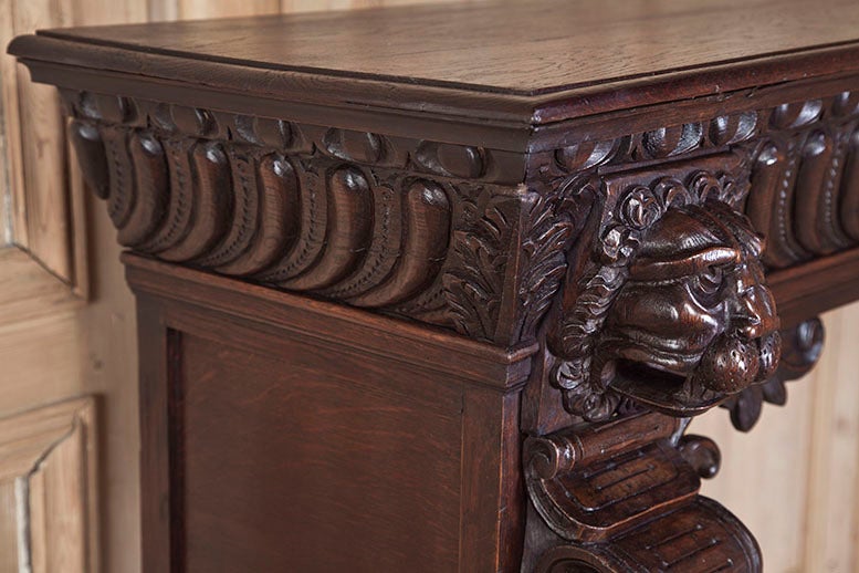 Crafted during the Art Nouveau period from solid European white oak, this exceptionally well-preserved fireplace mantel/surround features hand-carved sculpture on both sides depicting lions's heads, elaborate corbels with acanthus flourishes, and a