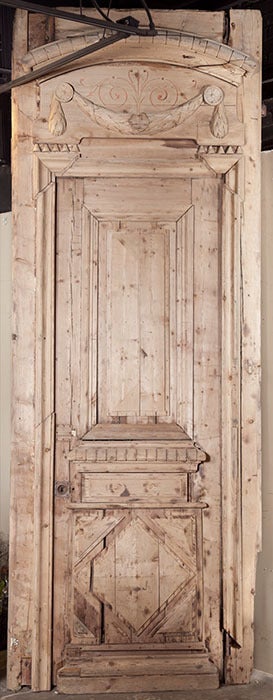 Crafted from solid yellow pine during the Napoleon III period, this handsome Louis XVI style door includes its original frame which features a transome with carved laurel garland and arched cornice. Finely molded from top to bottom, its panels are