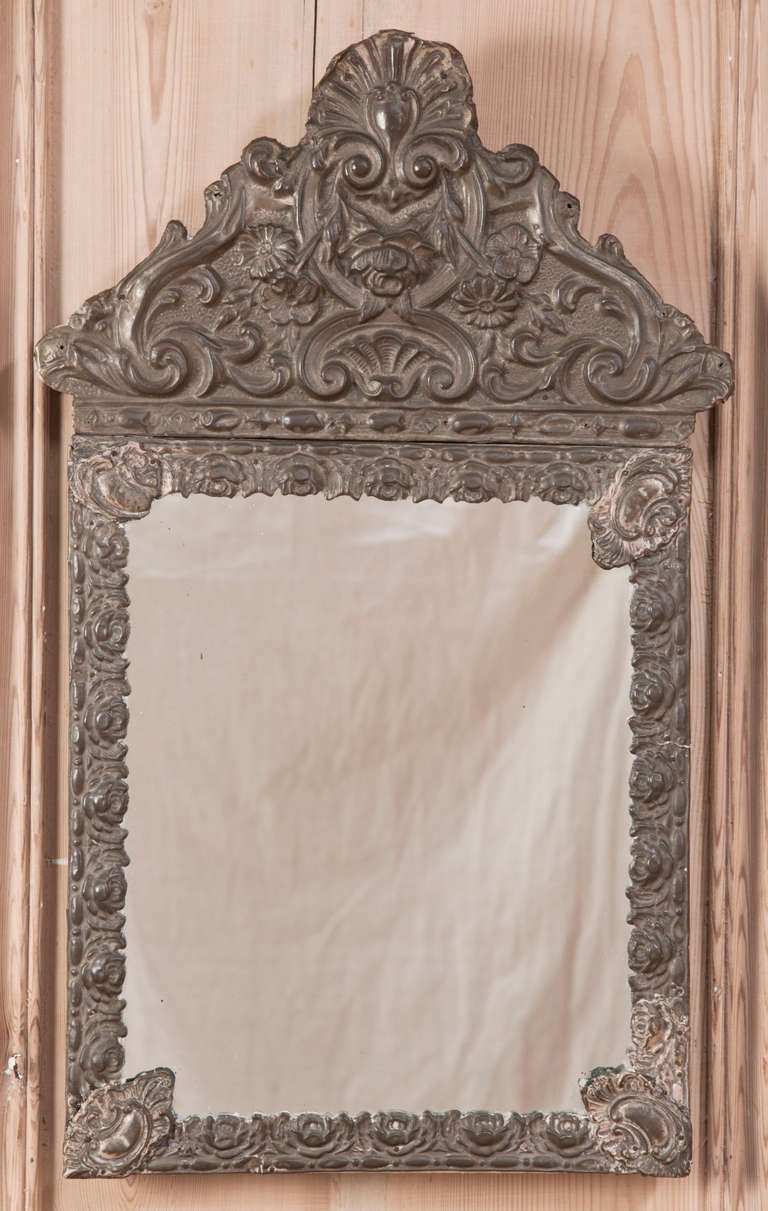 Originally used to help reflect candlelight into a room, diminutive mirrors such as this pair were nevertheless treated to a grand dose of style. Embossed in a spectacular floral and foliate pattern with an arched bouquet theme on top, the embossed