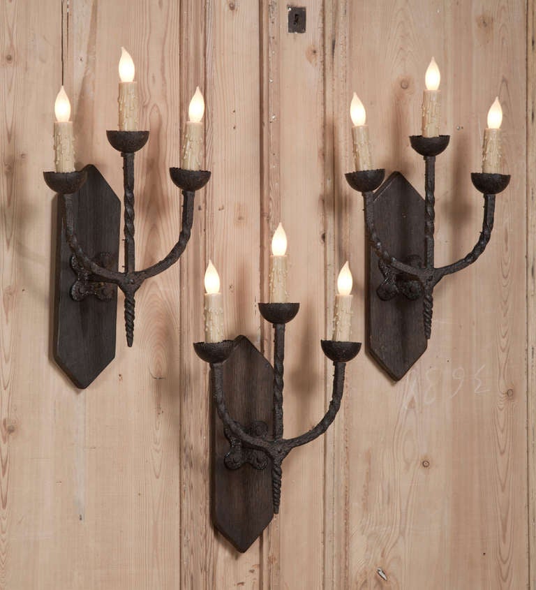 Originally designed for candles, this set of three sconces was salvaged from a beautiful old home and possess an excellent representation of hand-forged iron with a delightful Provincial look. Perfect for hallways, the staircase or anywhere a little