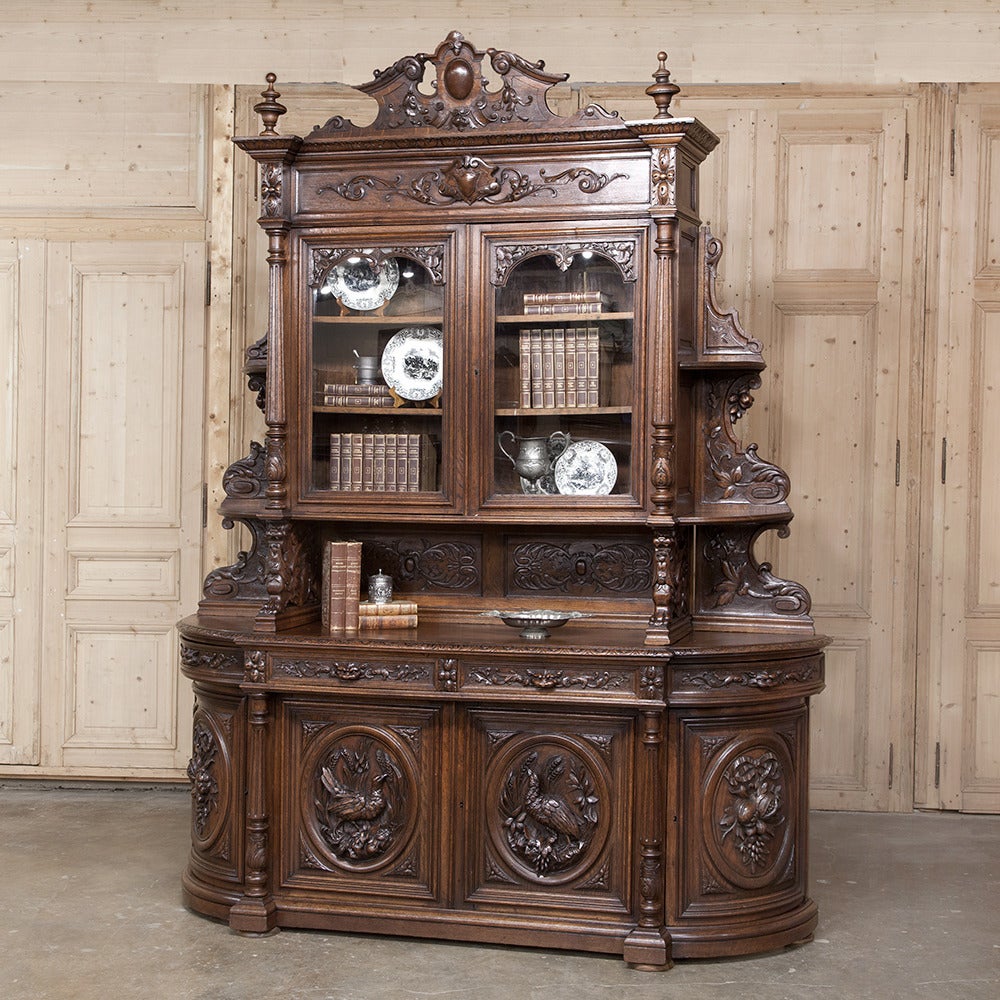Carved to perfection from the intricately formed crown to the boldy molded base, this stunning 19th Century Grand French Renaissance Two-Tiered Buffet features full-relief carvings of wildlife and della robia, or bounty of the earth.  The rounded