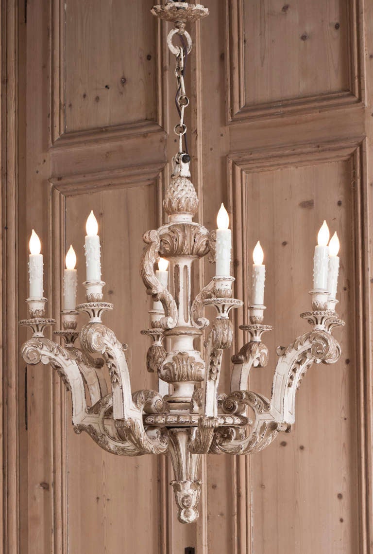 Hand-carved in the manner of Louis XIV, then given a painted finish with gold highlighting that has achieved a lovely patina over the decades, this chandelier is perfect for the Paris Country or 