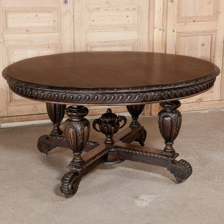Exhibiting an unusual expression of the Henri II Style, this Napoleon III Period Center Table is supported by four massive urn-shaped pediments that have been lavished with fine hand-carved detailing, matched by the large finial at the center of the