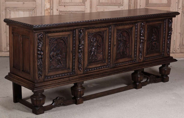 Raised upon carved urn pediments, this buffet features four individual scenes carved in full relief on each of the four doors, separated by della robia carvings on the pilasters. Hand-crafted from select European white oak to last for generations,