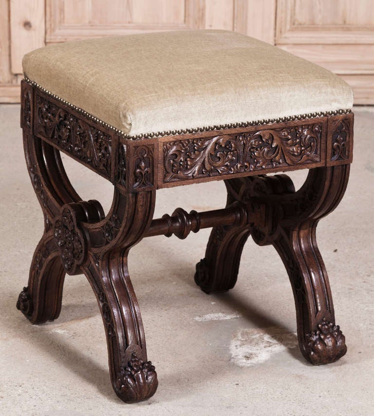 Sculpted from dense, old-growth French oak in the timeless Gothic manner, this footstool features carved embellishment over the entirety of its facades, including the insides of the legs, which are connected together with a turned stretcher.
