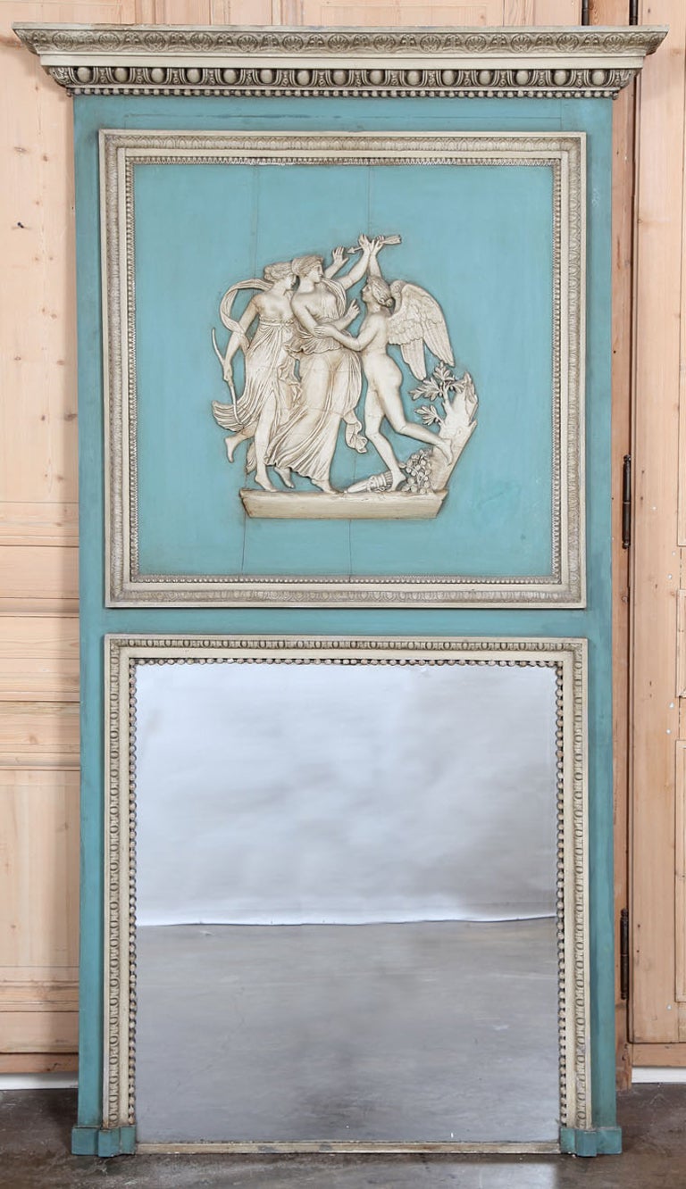 Almost seven feet in height, this trumeau will surely impress! Featuring its original pastel painted two-tone finish that has achieved a superlative patina over the past century, it boasts a generous mirror below and a stunning relief panel above