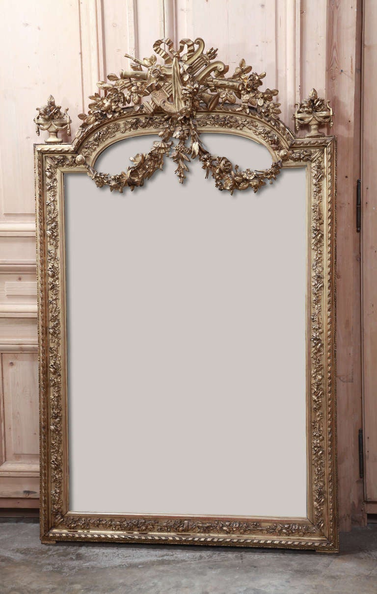 This spectacular 19th Century French Neoclassical Mirror boasts stunning detail and its original silvered mirror!  One can gaze for hours at the immaculate detail that abounds on the arched crown, with musical instruments, flowing ribbon with bow,