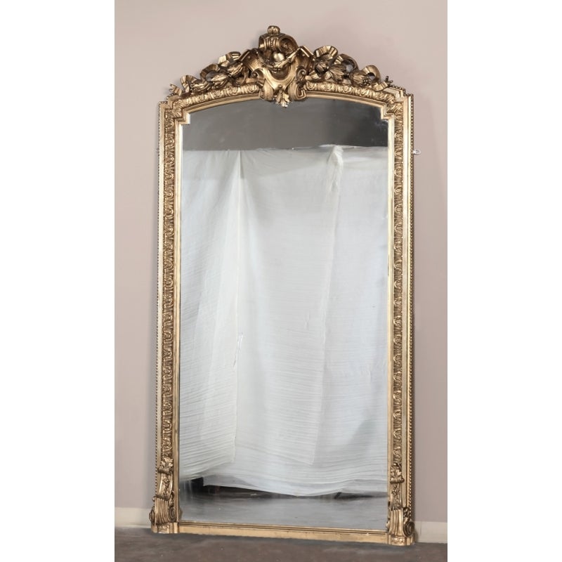 This Grand Regence gold d'ore mirror stands over 8 feet tall, and will command an instant presence in any room! Beautiful heraldic crest, scrollwork, foliates and detailed molding surround the glass, originally designed to reside in  French Chateau.