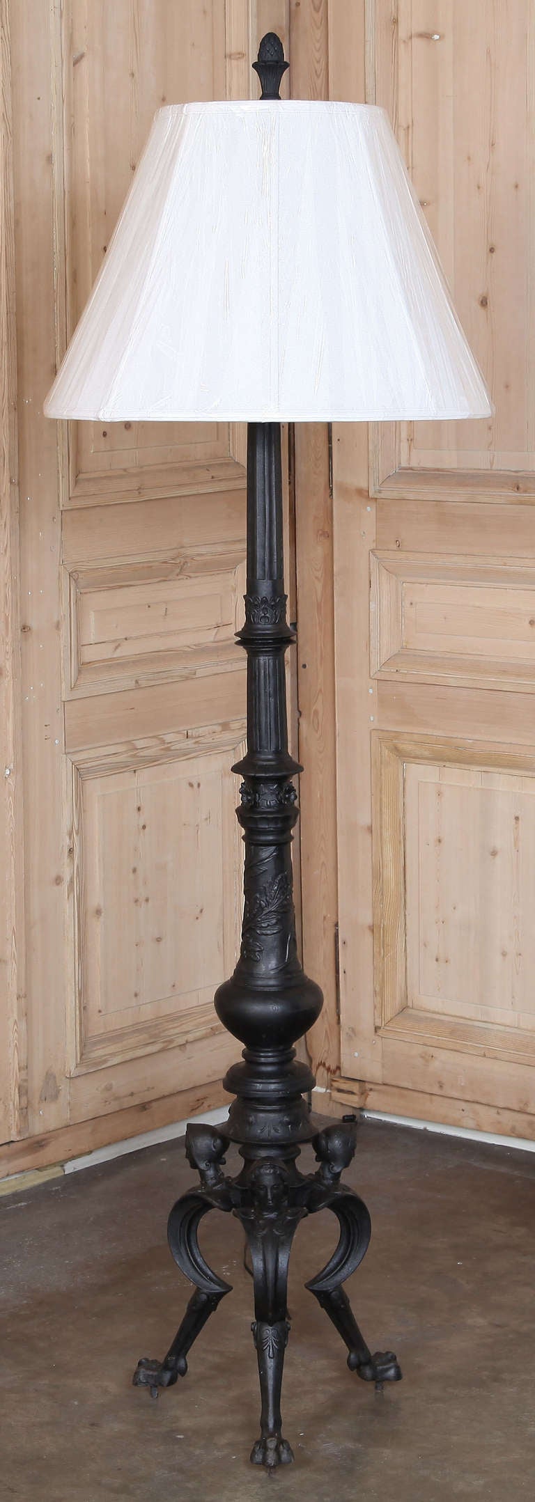 Cast from solid iron, this handsome lamp is wired to UL Standards and fitted with a hand-sewn silk shade. Exceptional detail abounds from the paw feet and angels' heads on the tripod base, up the intricately detailed shaft to the capital adorned