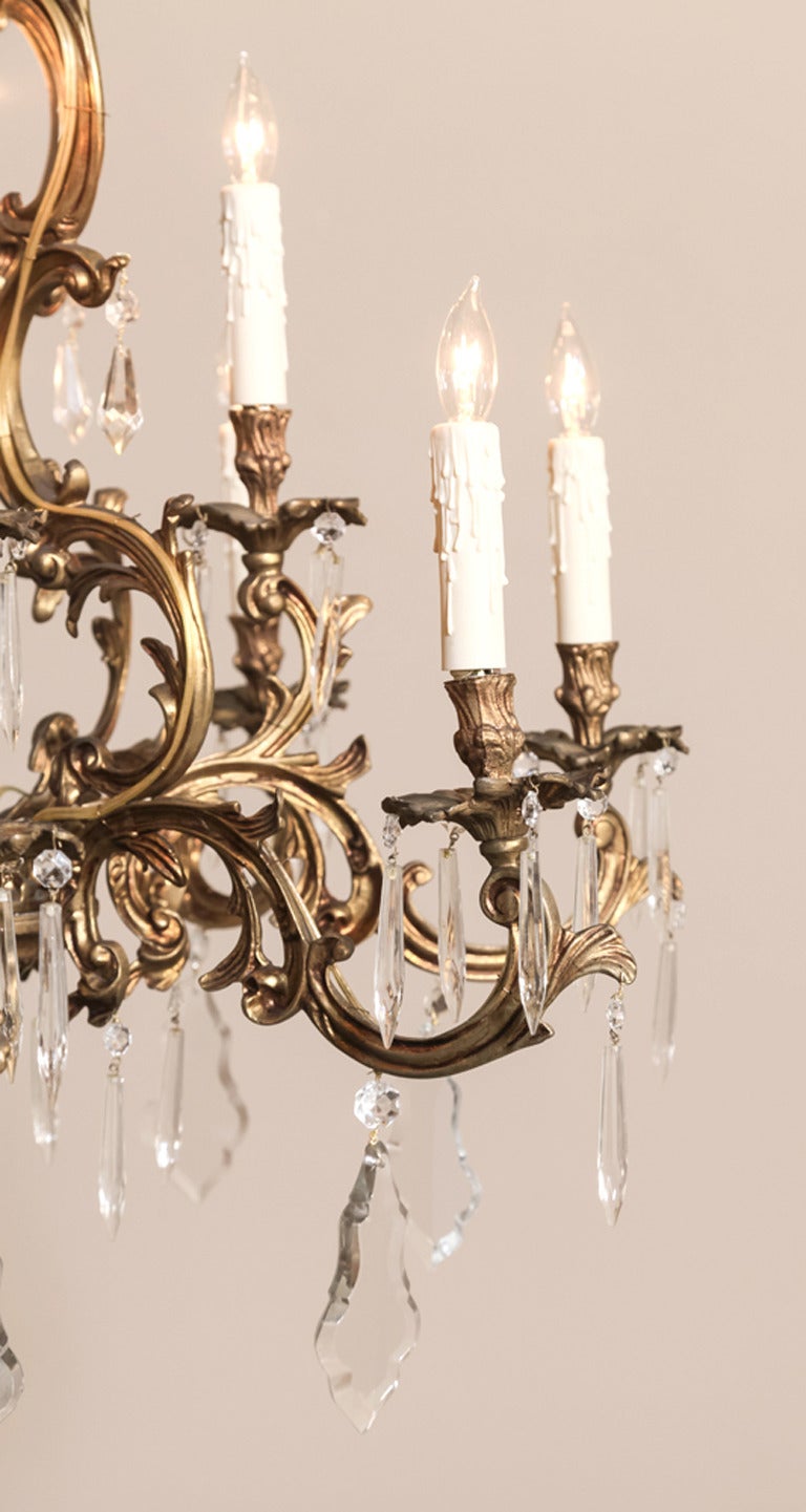 Beautifully draped with hand-cut crystals, this Italian Rococo cast brass sixteen-light chandelier was handcrafted in Italy by master metalsmiths, and survives with a length of chain and its original canopy. Fully electrified, it is the perfect