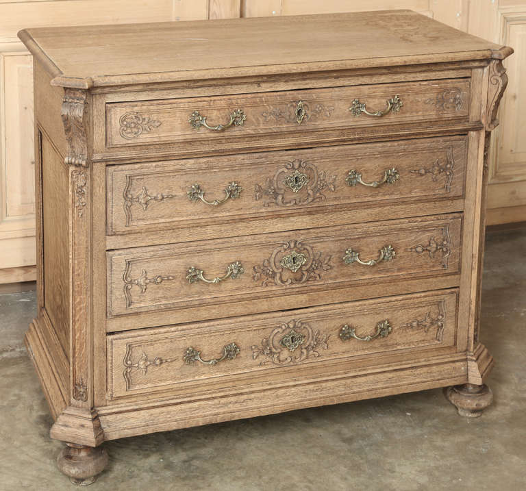 Benchmade from solid French stripped oak, carved with stylized floral and foliates, designed with mitered corners and fitted with cast brass pulls, all with a delightful patinaed rustic natural finish. 
Circa mid-1900s 
Measures 33.5 x 39.5 x 19.5.
