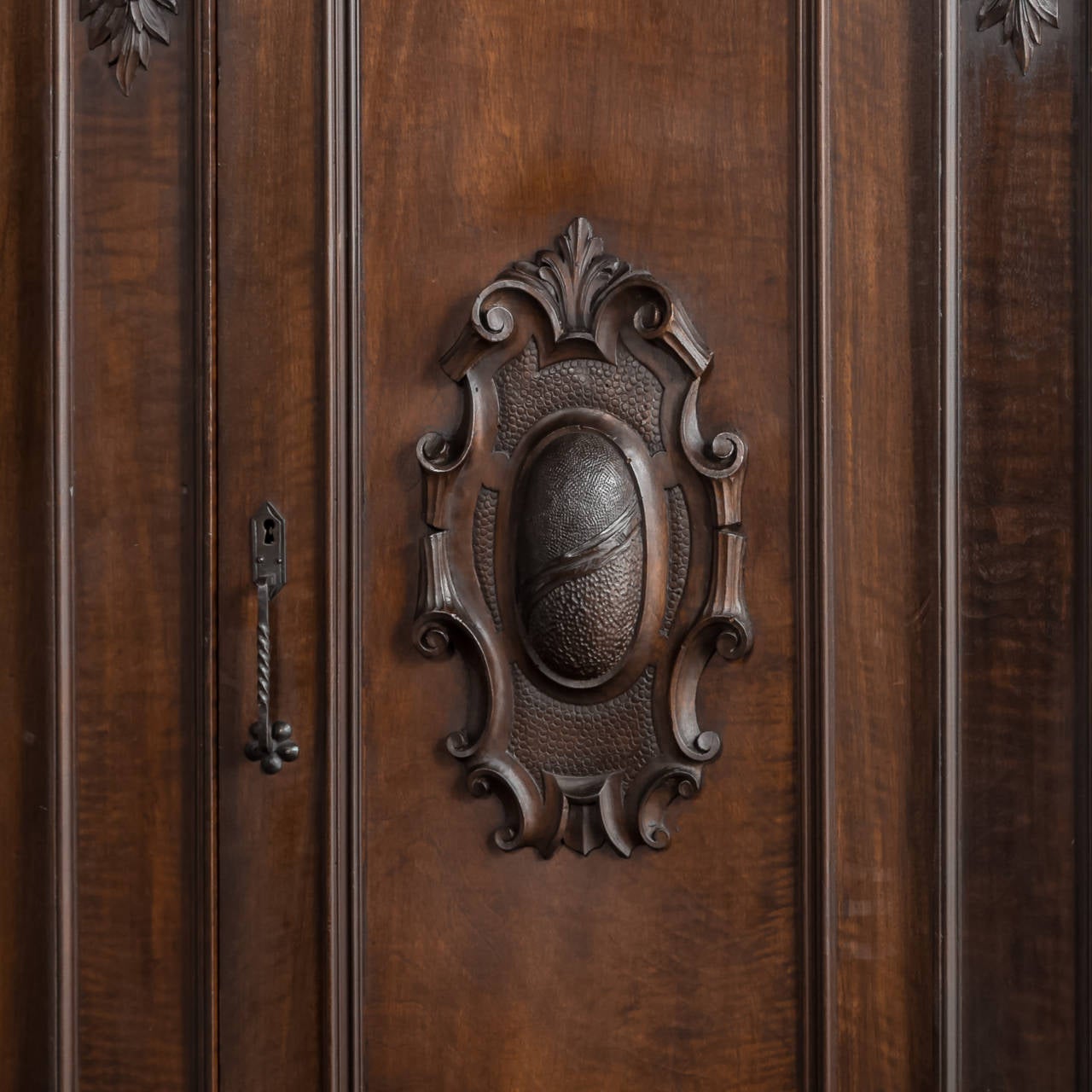 Benchmade from fine Italian walnut and hand-carved with a glorious expression of Renaissance-inspired embellishment in full relief, this triple armoire will provide copious amounts of stylish storage. Heraldic crests centered on the door panels are