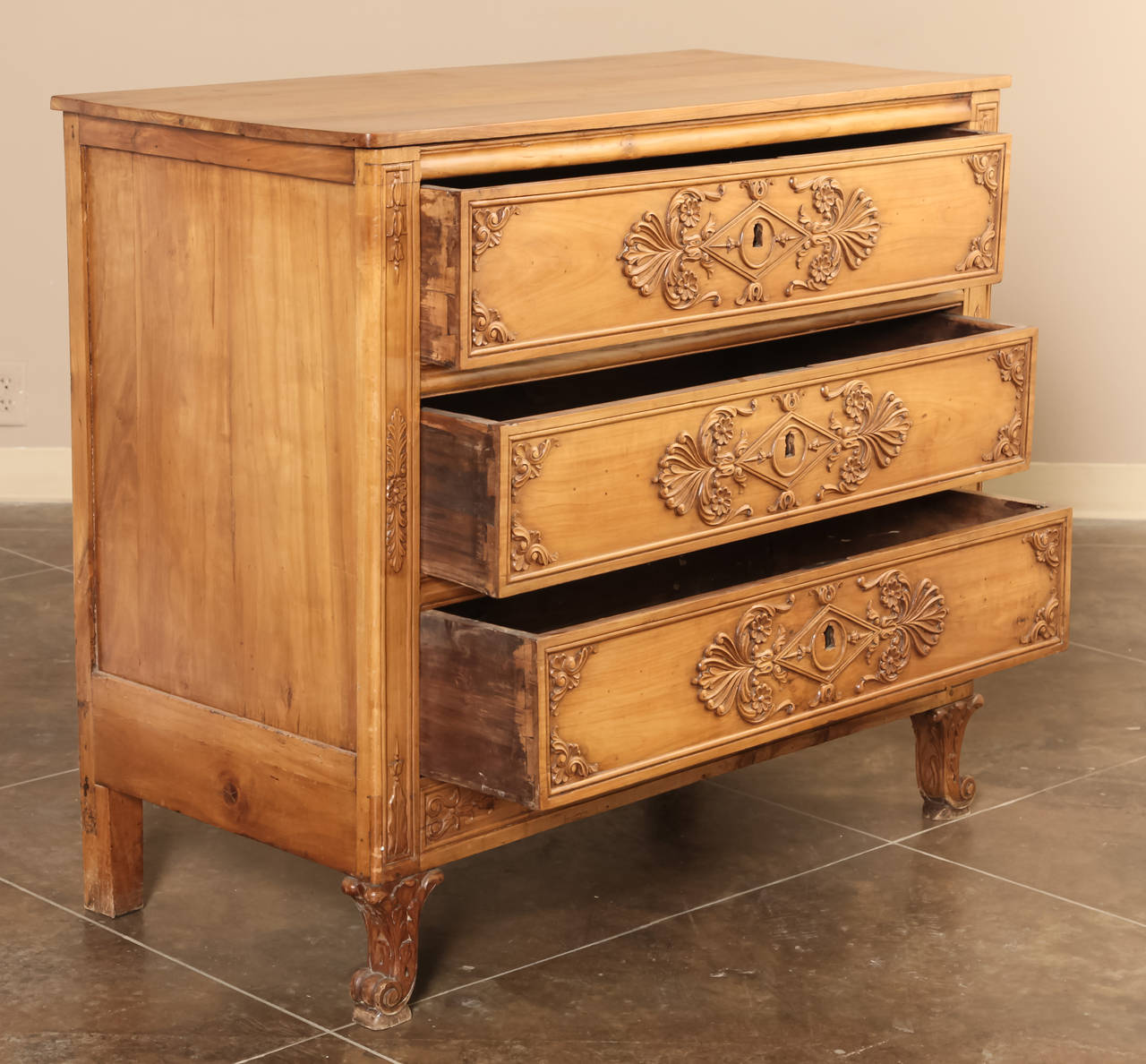 Handcrafted from fine French applewood with an intriguing style statement, this Charles X-period commode will work in any room of the home or office. Unusual bas relief carving across the drawer facades combines with the equally unusual feet and