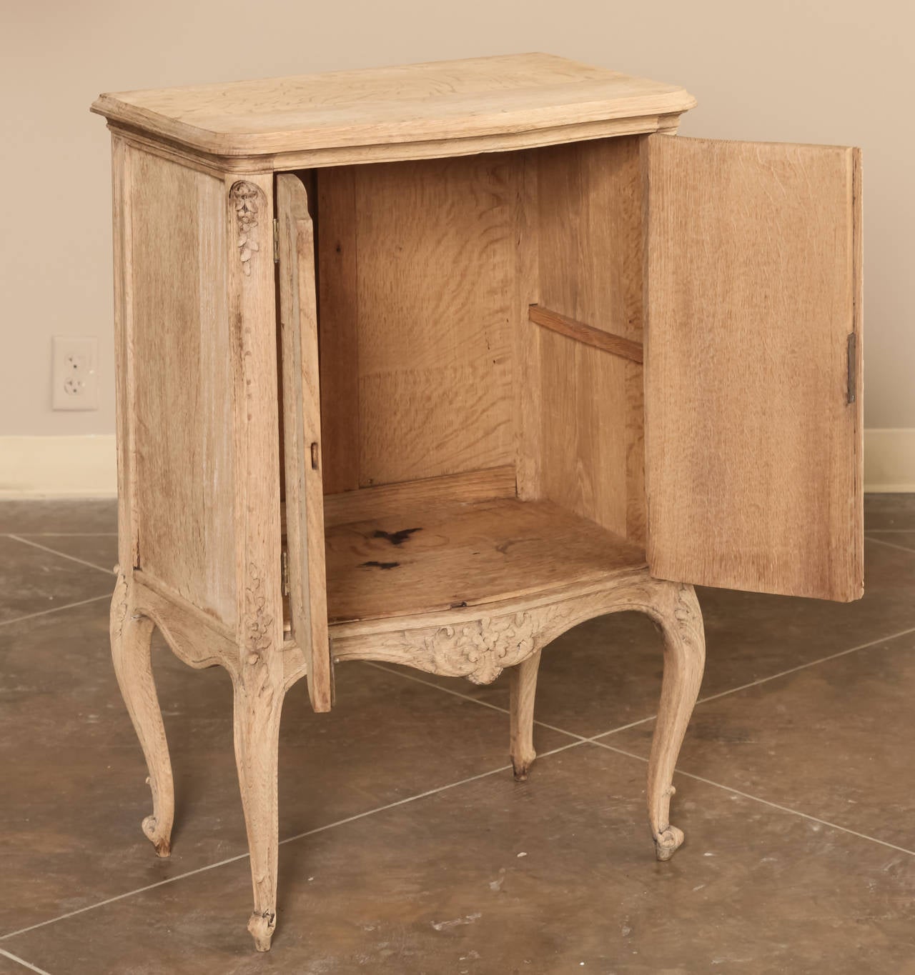 Hand-carved to perfection by talented artisans, this petite stripped oak Country French buffet, called a confiturier in France, features carved musical instruments  on each door bursting with ribbons and romantic motifs, in deference to Queen Marie