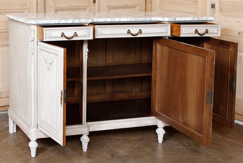For a subtle, understated Neoclassical elegance, the Louis XVI style is practically unequalled, and this superb antique French buffet is a great example. Crafted from solid French walnut, it features carved embellishments only at the top of the door