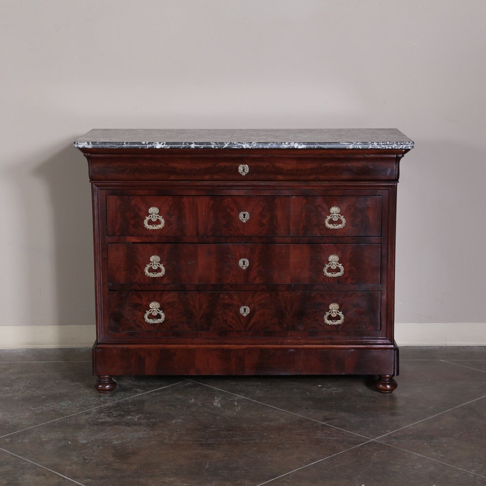 This impressive Louis Philippe period mahogany commode features the naturalistic beauty of the exotic imported wood made more apparent by the tailored lines of the architecture, yet accentuated by the brilliance of the cast bronze pulls and