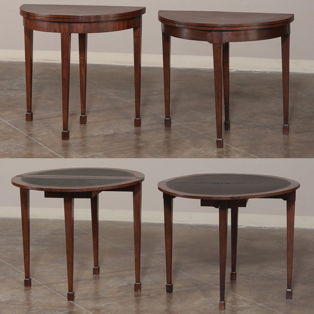 Pair of 19th century demilune consoles disguises the fact that they also double as game tables! Handcrafted from exotic imported mahogany, each features a fourth leg in back that draws out, allowing one to flip open the tabletop to create a