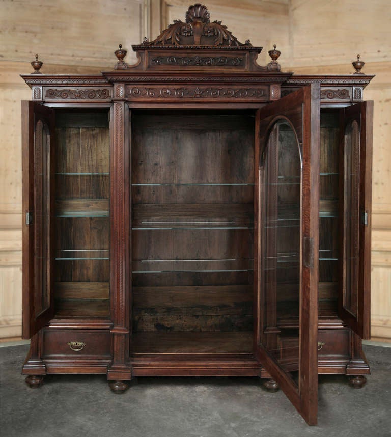 With a majestic crown soaring over eight and a half feet tall, and a triple casework below almost eight feet in width, this armoire was truly designed to serve as a peerless display caset, rendered entirely in fine Italian walnut. Step-front center