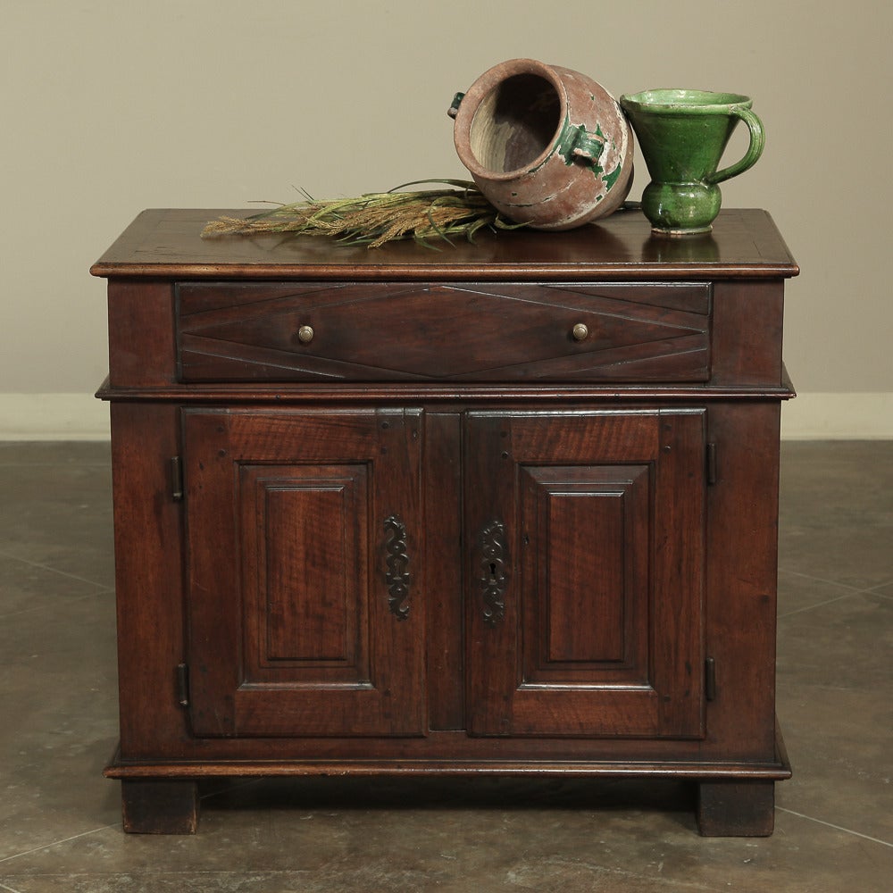 Darling antique cabinet handcrafted during the early years of the 19th century, this Directoire period country French low buffet represented an effort by rural craftsmen to emulate the styles set forth by the court in Paris. Indigenous woods and