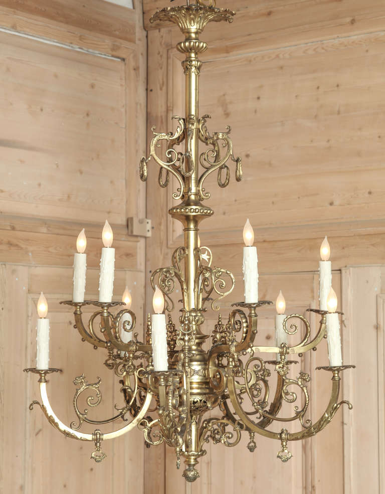 Forged from solid bronze and brass, this impressive chandelier follows the graceful form of the Baroque style. Originally configured to provide open gas flames, it has been converted to UL Standard electric lighting by our expert staff, and will