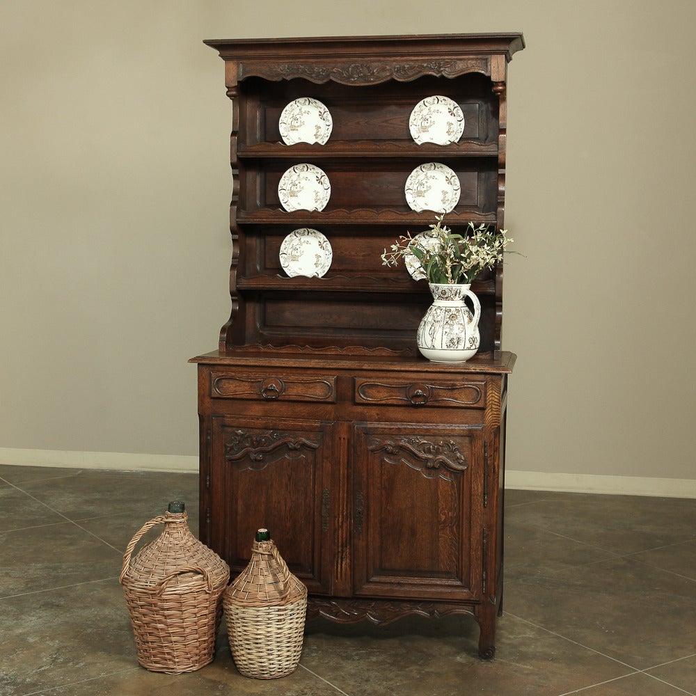 A bit narrower than most, this charming Country French Vaisselier is perfect for displaying your choice china or collectibles, while storing other items in the pair of drawers and cabinets below. Finely carved with florals, foliates and scrollwork.