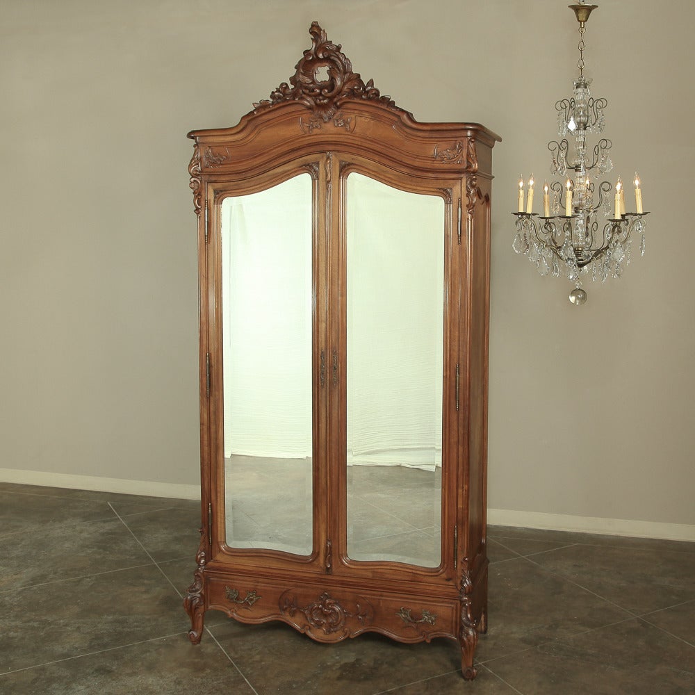 Exquisitely handcrafted during the latter decades of the 19th century, this impressive Rococo armoire was created from fine French walnut to last for centuries! The original hand-beveled mirrors which follow the framework of the doors provide a