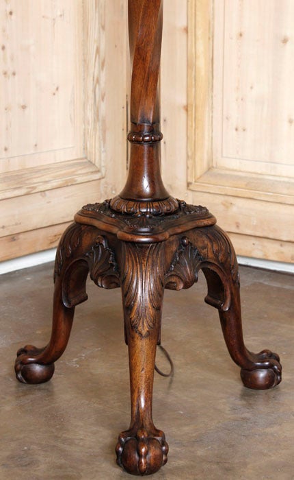 Featuring signature claw and ball feet with a tripod base with beautifully crafted in walnut legs, this intriguing antique French Renaissance style floor lamp boasts a two-section appearance with spiral faceting and finely carved accents.  Wired to