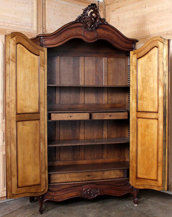 Considered by all the experts to be the most beautiful of all European furniture woods, French walnut continues to rank among the top five across the board! This armoire, carved in the Louis XV manner, features a boldly arched crown with cartouche