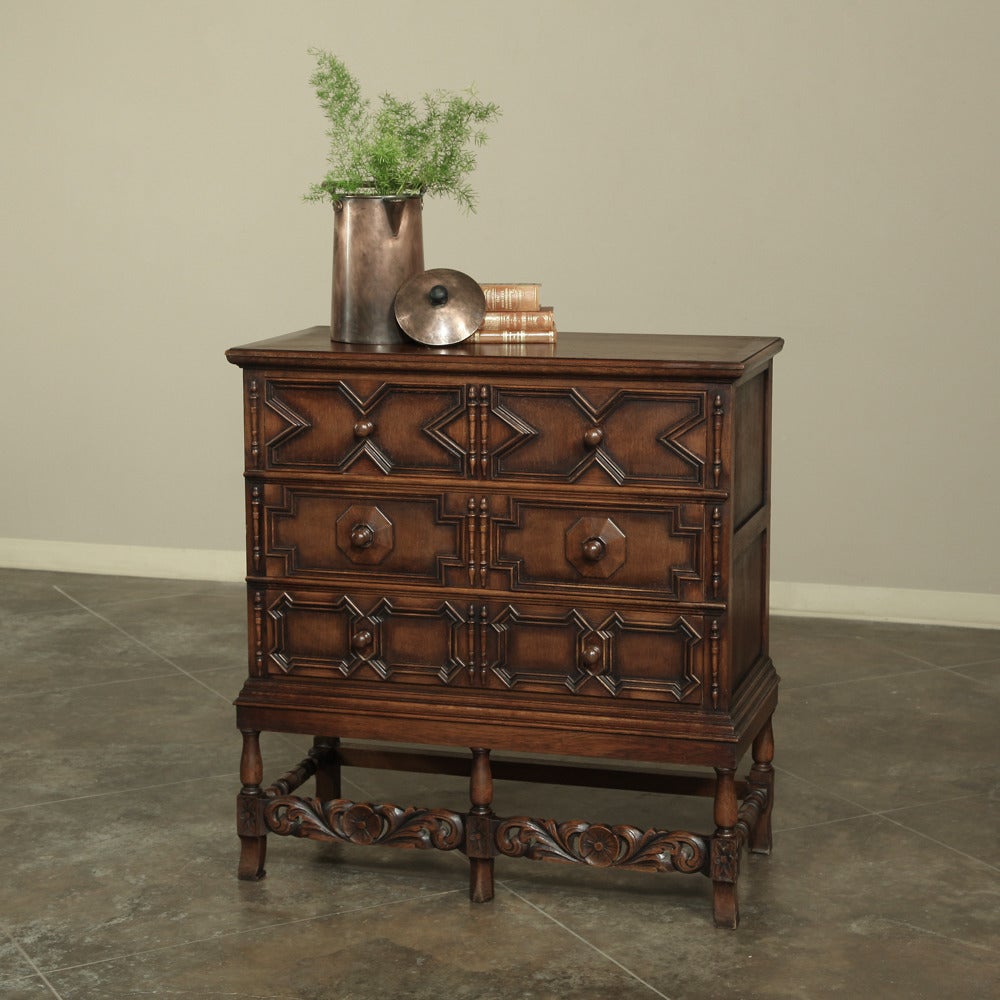 Set upon turned legs connected with carved stretchers, this handsome chest of drawers was adorned with half columns and geometrically inspired molding in the Jacobean tradition to create a functional yet stylishly subtle piece.  The raised leg