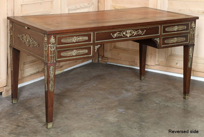 Magnificently crafted from exotic imported mahogany, this Empire style desk was created during the Second Empire in a revival of the epoch created by Napoleon Bonaparte. The leather top is augmented by pull-out side surfaces also upholstered in