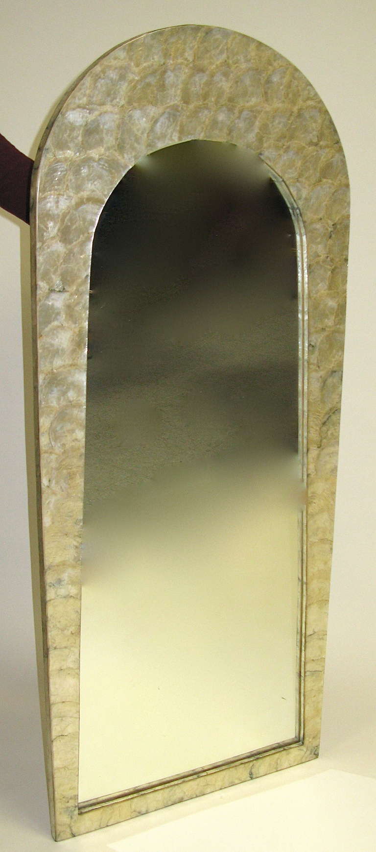 Shimmery capiz shells make up the frame of this rounded top mirror. Mirror is a bit hazy, but still clear. (Could be replaced) Shells have heavy clear coating. Frame is in very good condition.