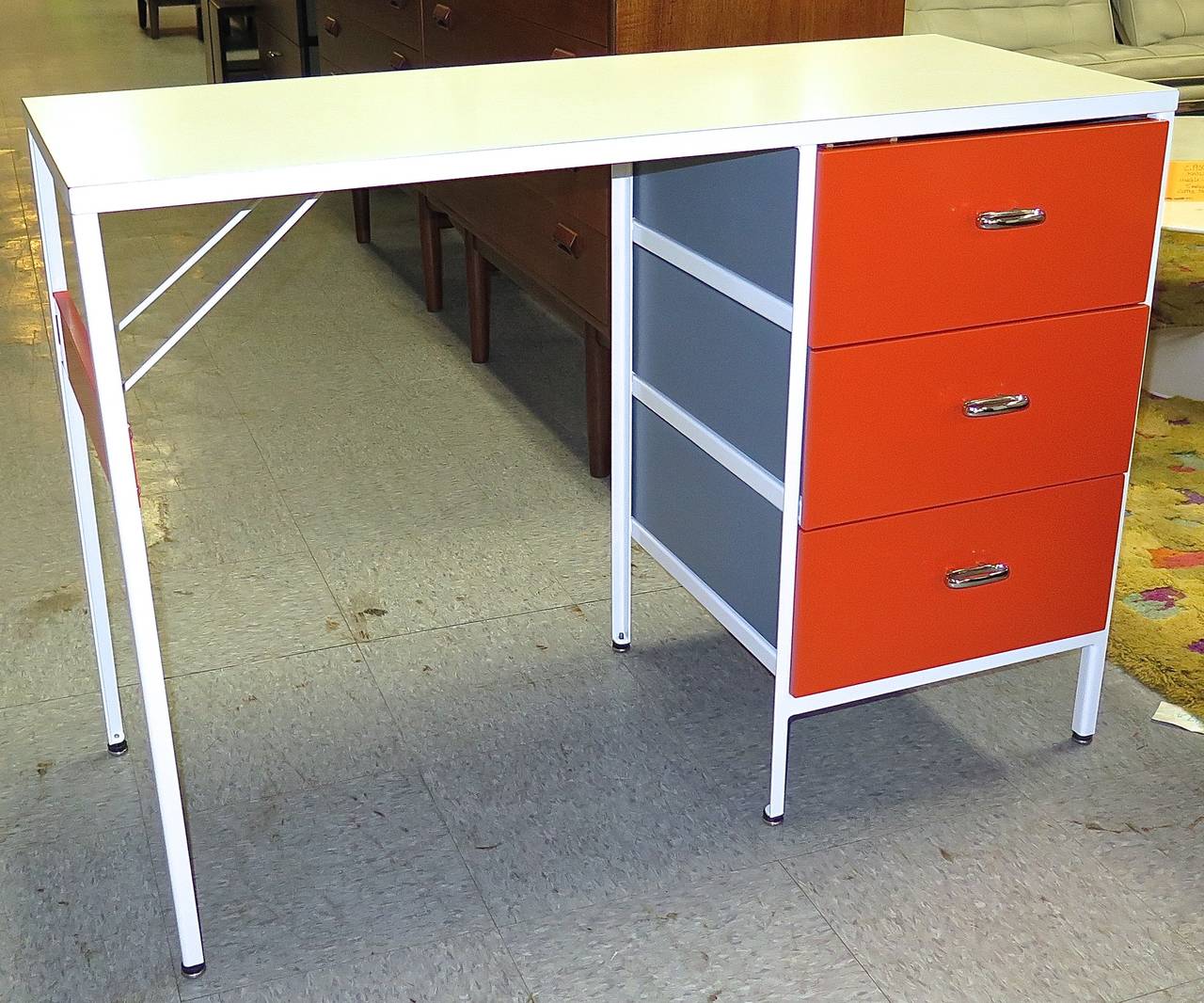 Original label. Repainted in bright tangerine orange color with blue-grey drawers. Excellent condition. Top laminate has some marks.