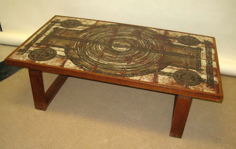 Solid teak table with textured clay tile top. Colors of brown, cream, red and green come together to really make this table a great conversation piece. Nice vintage condition. No chips or breaks in top.