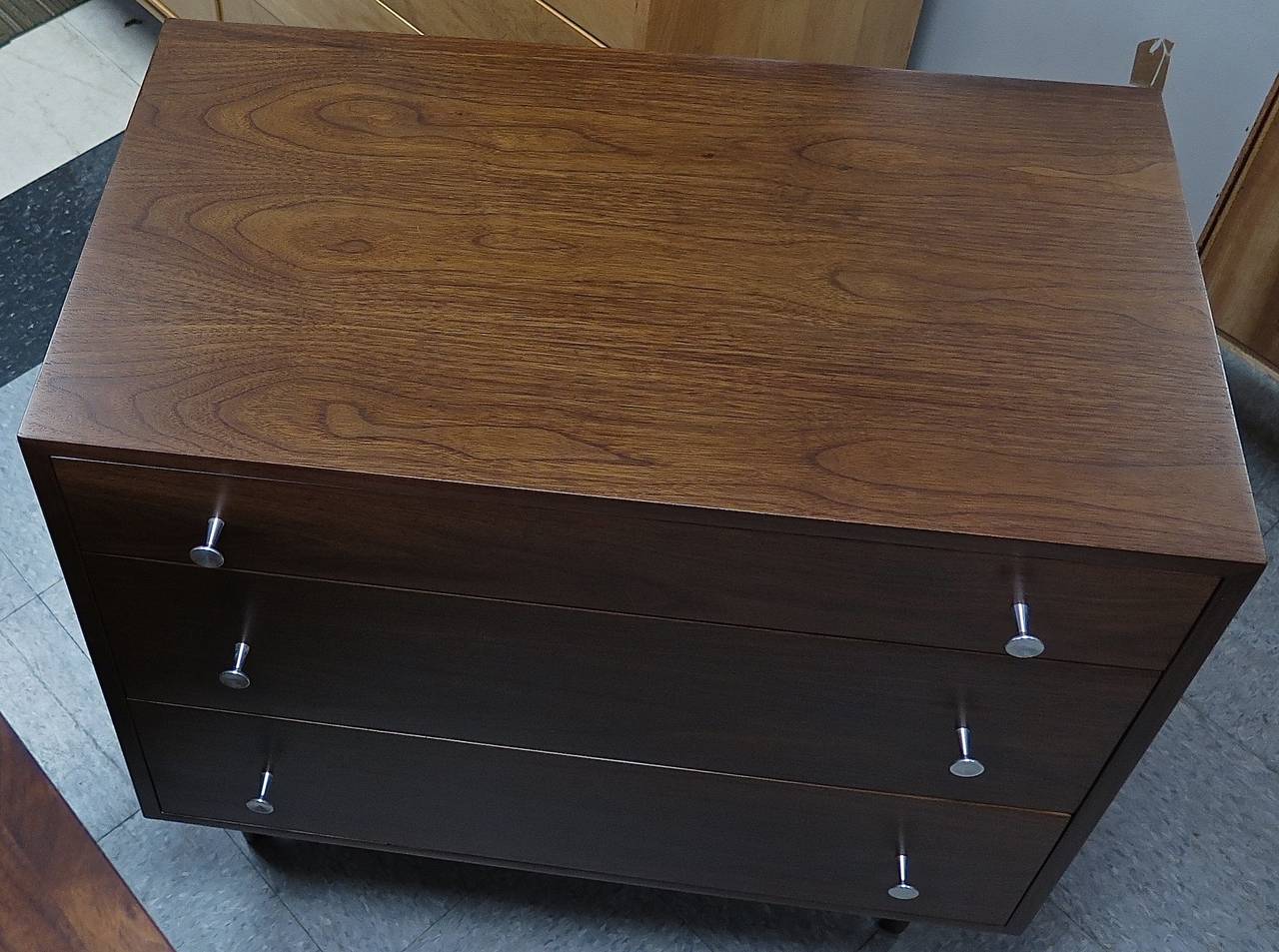 Labeled. Perfectly proportioned smaller sized dresser. Nice warm brown toned walnut. Aluminum pulls. Some dark spots under the new finish on top. Great piece!