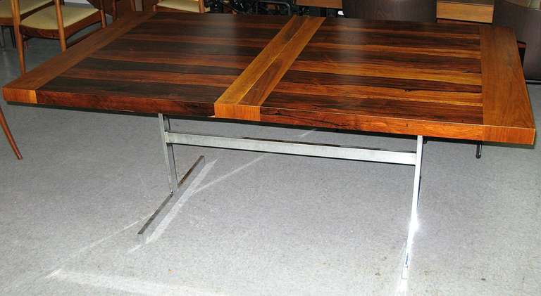 Chrome trestle base. Excellent condition. Amazing rosewood grain with bleached mahogany highlights and leaves. Top has been restored with few minor blemishes. Two 18 inch leaves extend the table to 108 inches . Actual color is a bit more toned down