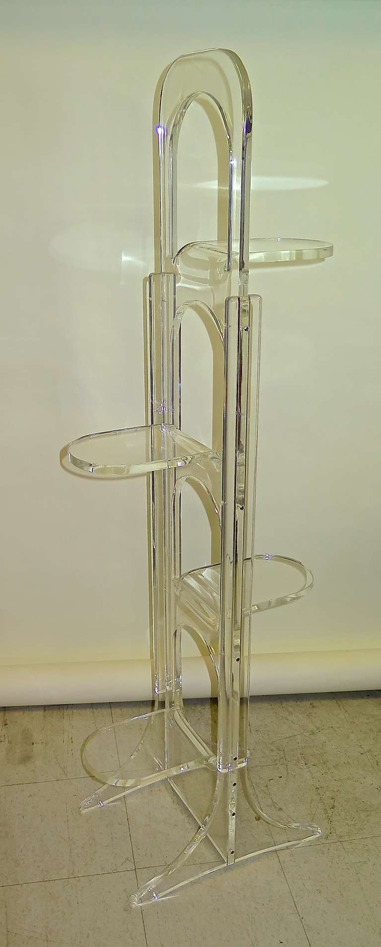 Unusual shape. 5/8 inches thick lucite. 4 bent shelves. Few scratches and scuffs. Great for small spaces.