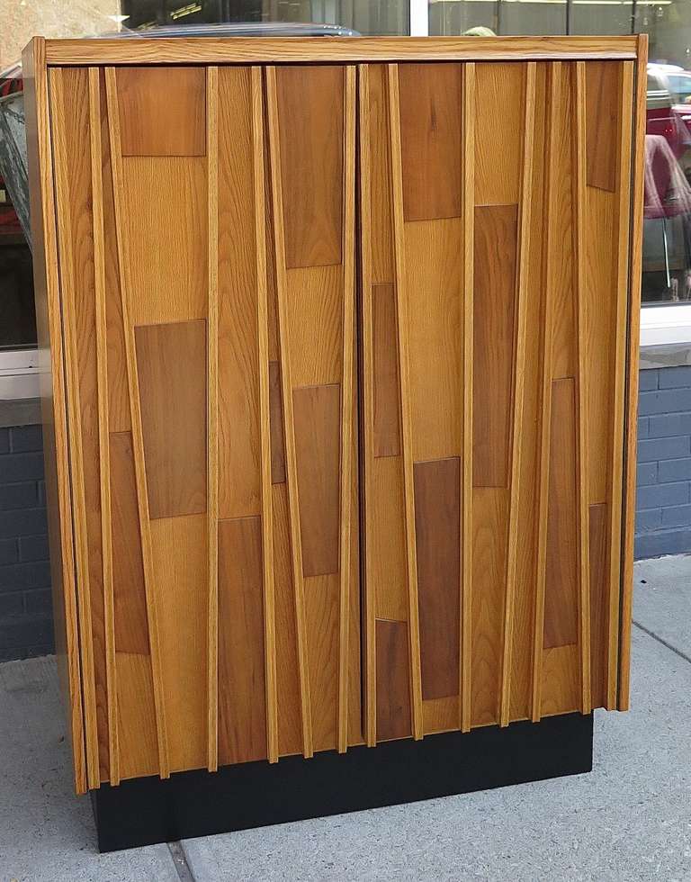 Restored. Black plinth base. Oak veneer, solid wood front with both walnut and oak. Behind doors has storage with adjustable shelves and 2 drawers on bottom.