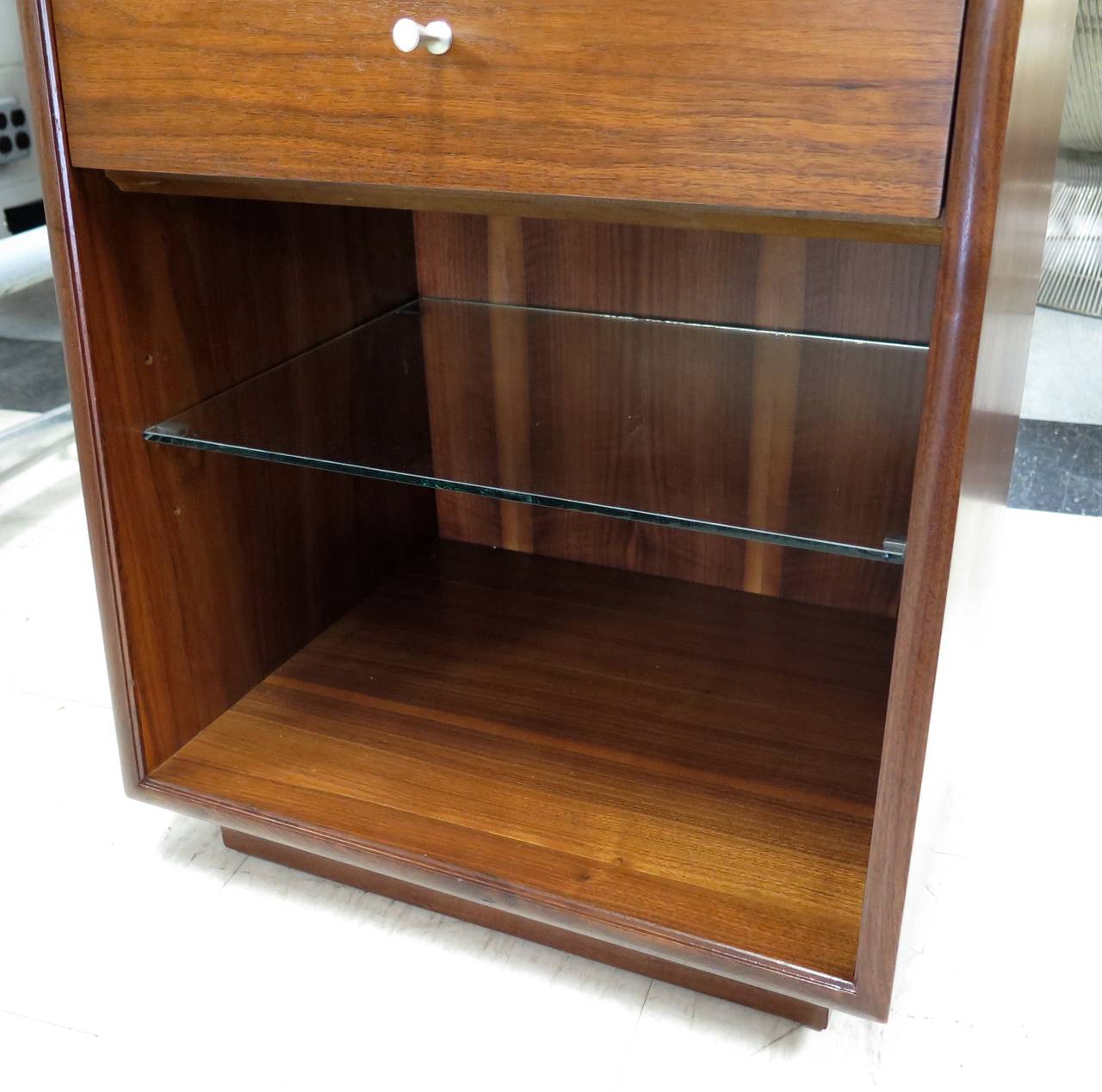 Restored. Walnut wood construction. Glass shelf. New knobs. Few small dings on edge. Top measures 14" deep, bottom 15.5" deep. Nice looking stands.