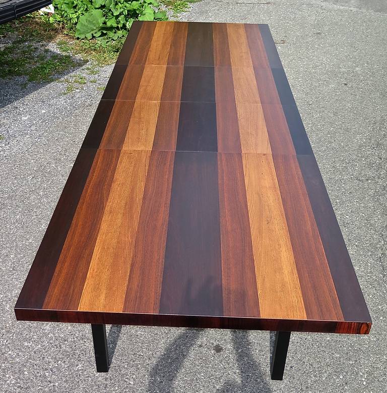 Restored. Nice strong colors. Combination of rosewood, walnut, and  light mahogany.  Black lacquer skirt and legs. Few minor scuffs and edge wear. Has two, 20 inch leaves. Total open length of 112 inches.