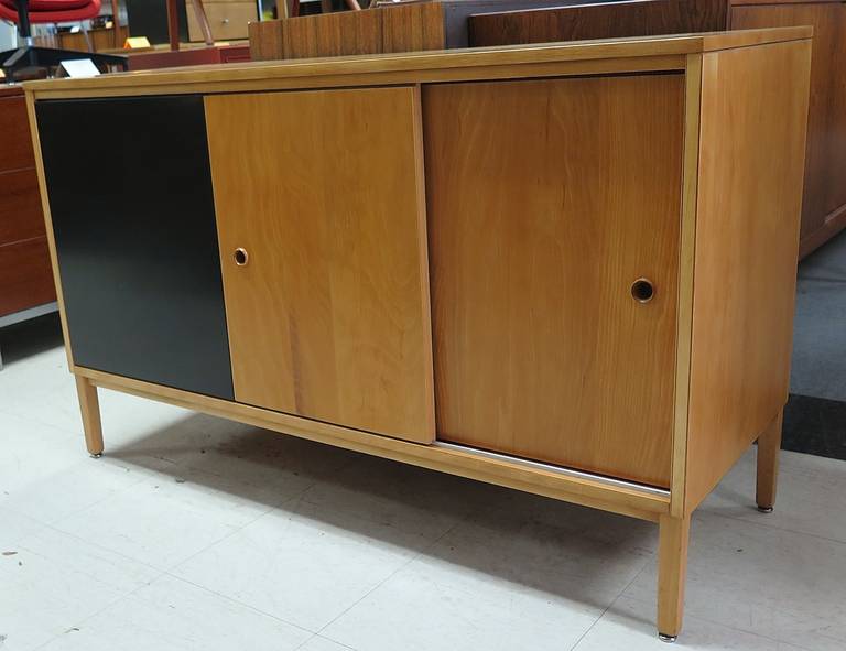 Restored. Signed. Birch veneer and solid wood construction. One adjustable shelf. Two sliding doors. One black lacquer sliding door. Very unusual piece!