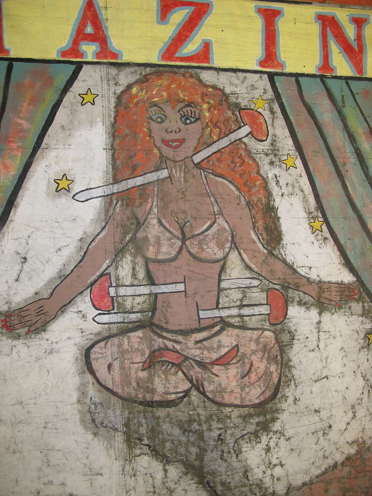 Toile avec support supérieur en bois. Double face. Le côté Fire King a été repeint à un moment donné. La femme de la pelote d'épingles a peu de surpeinture. Usure typique d'une utilisation en extérieur. Superbe couleur.
