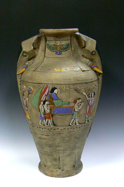 This large and impressive porcelain urn was produced by Julius Dressler. It features stylized elephant handles and is decorated with high glaze egyptian scenes upon a matte ground with incised decoration. Signed.

Dressler's art pottery factory