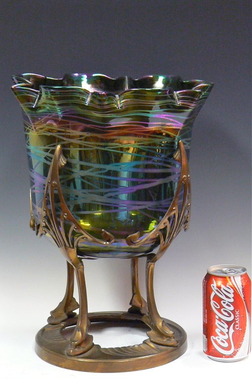 This is a very large and stylish vase mounted in a gilt metal holder. The rainbow like glass is green/blue with criss crossing iridescent silver rainbow bands. Though this type of art glass is commonly referred to as Loetz, it is more likely Kralik.