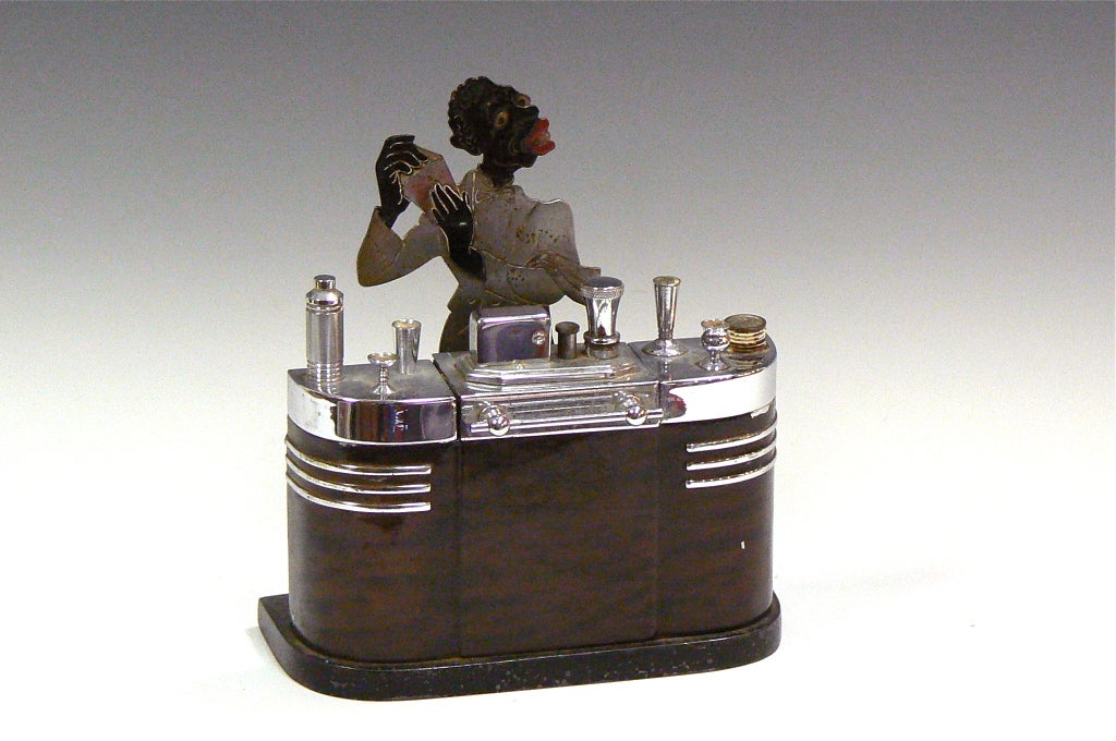 This desirable Ronson figural lighter features a black bartender rendered in iconographic darky form. It is collectible for the tobacciana collector as well as black memorabilia ethnographic collector. The streamline art deco bar encloses built in